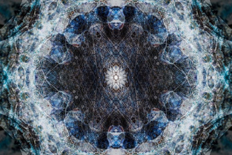A kaleidoscopic pattern made up of a light outer ring of overlapping shades giving way to a bluer ring and then a central circle with a white circular pattern in the middle. 