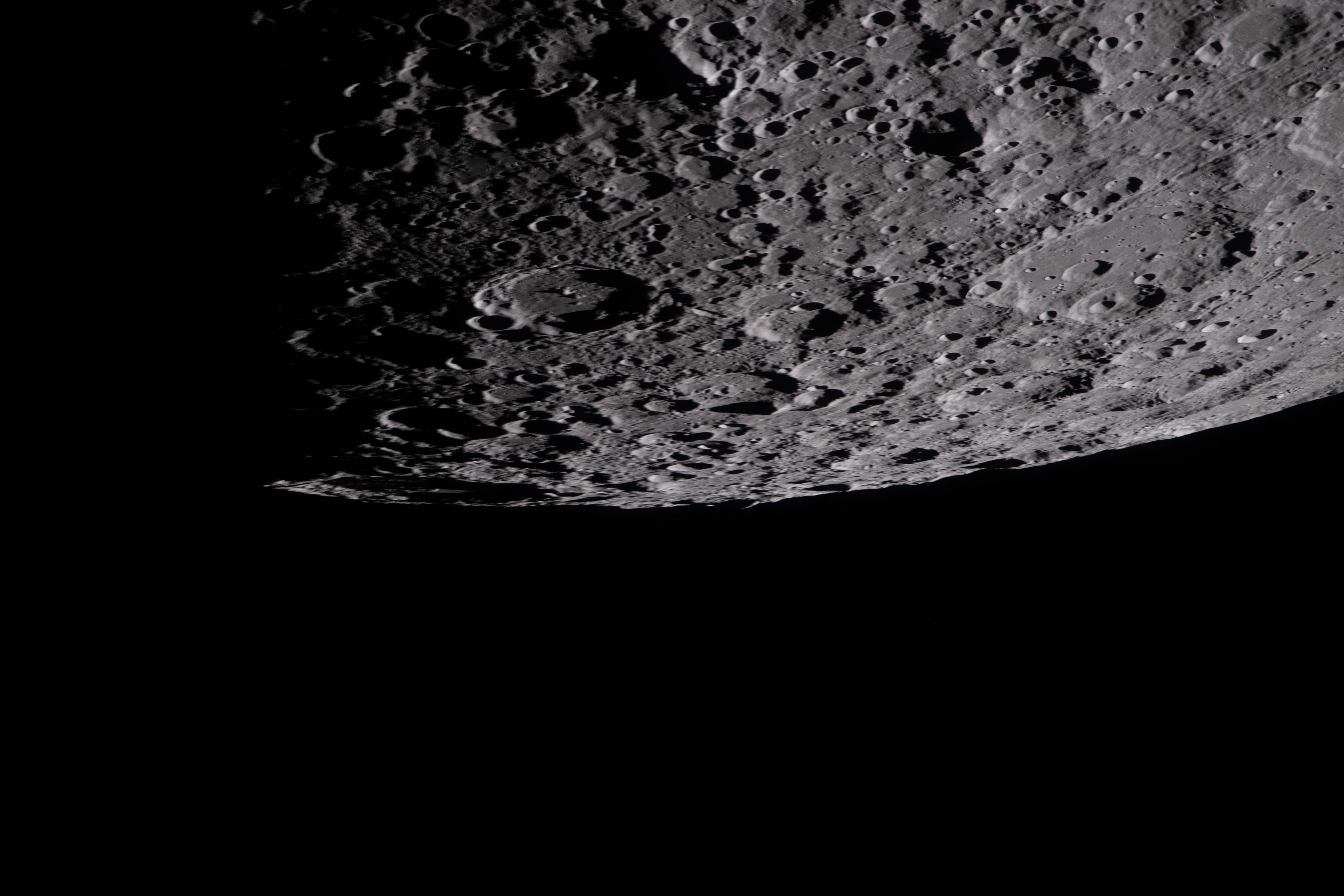the cratered surface of the Moon is seen in this image, where the moon occupies the top halg