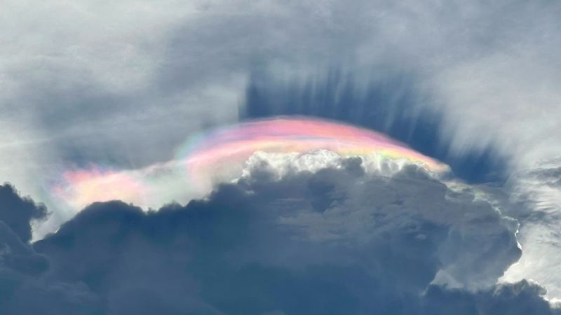 a lenticular cloud lit up by a rainbow of colors, in a phenomenon known as cloud iridescence.