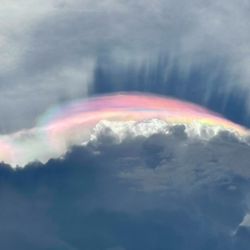 a lenticular cloud lit up by a rainbow of colors, in a phenomenon known as cloud iridescence.