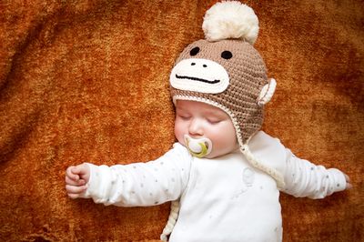 baby sleeping with pacifier wearing knitted monkey hat