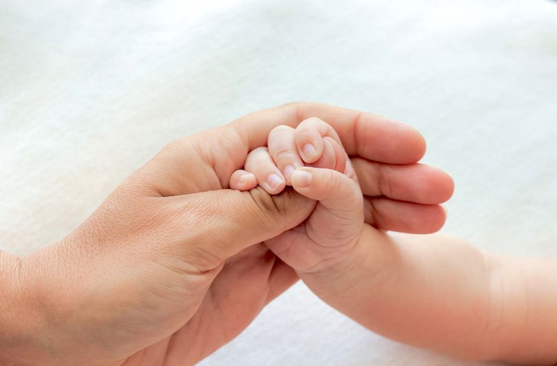 Baby holding adult thumb