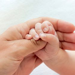 Baby holding adult thumb