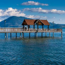 a pier jutting out onto Clear Lake in California on a sunny day, mountains are visible in the background