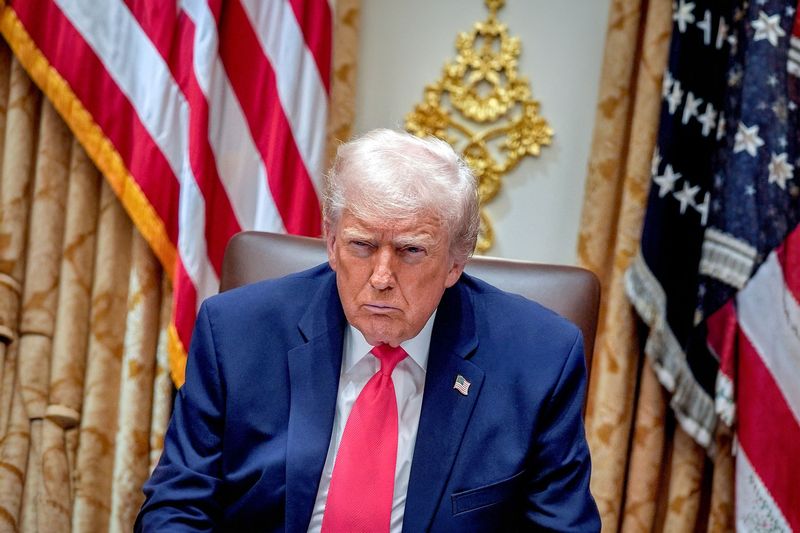 Trump looking at the camera. behind him two US flags
