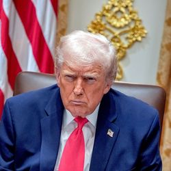 Trump looking at the camera. behind him two US flags