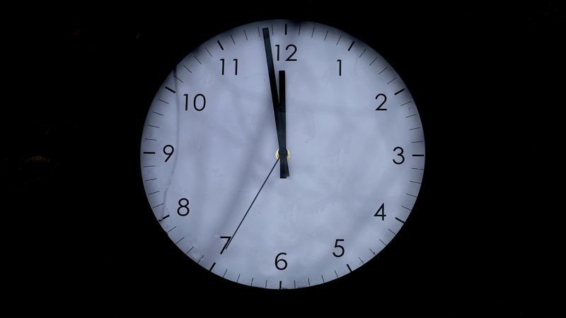A clock in the dark showing 85 seconds to midnight.