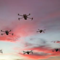 ten drones are seen flying in formation in the dusky sky