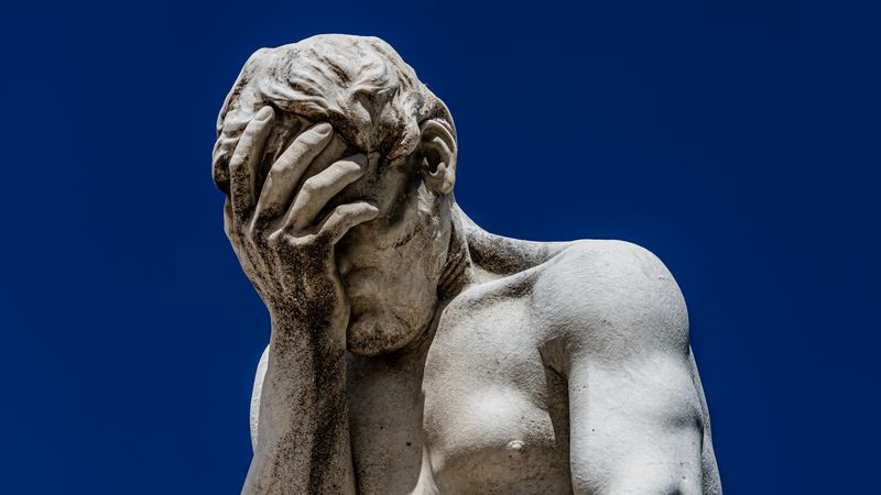 a white marble statue that appears to be faceplaming itself