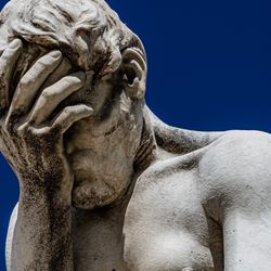 a white marble statue that appears to be faceplaming itself
