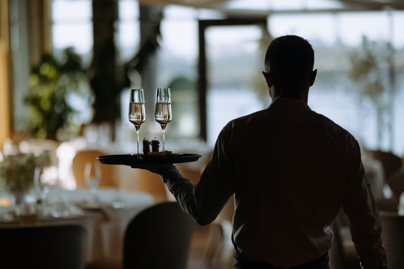 A professional waiter serves sparkling drinks at a modern restaurant, creating an elegant dining experience.