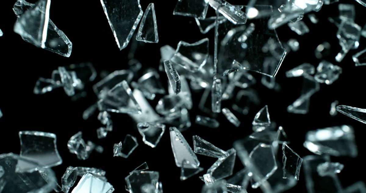 Shattered glass fragments captured in mid-air against a black background.