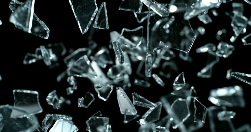 Shattered glass fragments captured in mid-air against a black background.