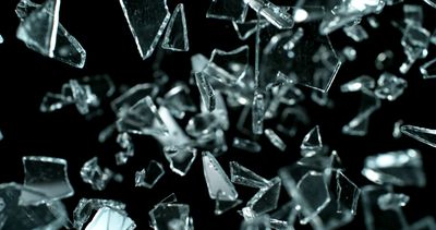 Shattered glass fragments captured in mid-air against a black background.