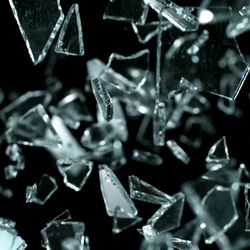 Shattered glass fragments captured in mid-air against a black background.