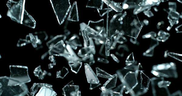 Shattered glass fragments captured in mid-air against a black background.