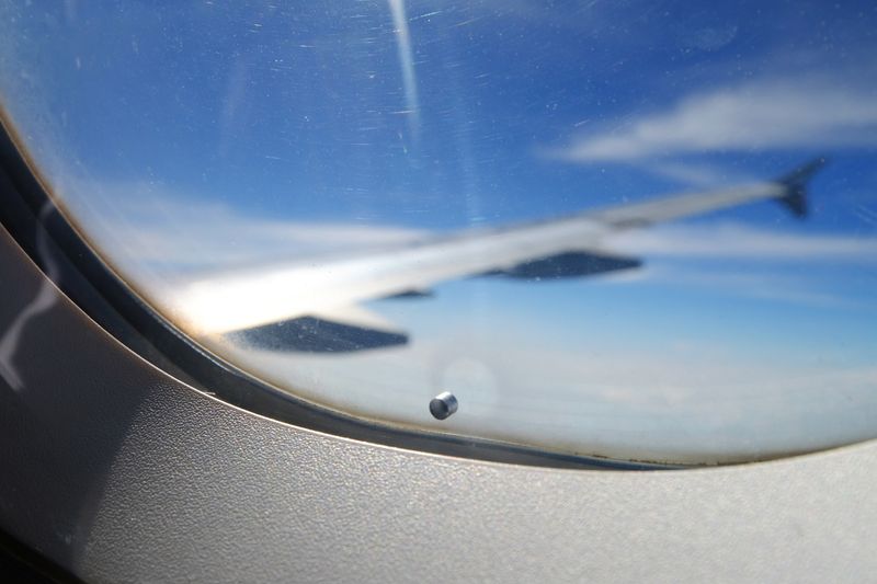 A tiny "breather hole" or "bleed hole" on the window of an airplane.