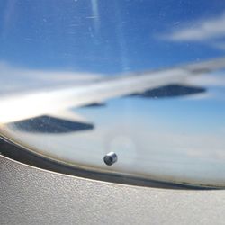 A tiny "breather hole" or "bleed hole" on the window of an airplane.