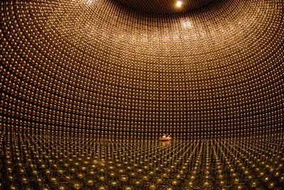 The vast interior of the super kamiokande detector, whose walls are lined with gold photomultiplier tubes.