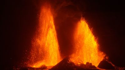 Two bright orange lava fountains erupting against a dark sky