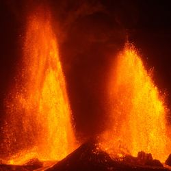 Two bright orange lava fountains erupting against a dark sky