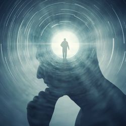 A conceptual image showing man's silhouette against a darker backdrop. The man is position on profile, facing to the left and appears to be rubbing his chin in thought. The center of his head shows a bright circle with a smaller silhouette of a man walking in it. This small circle is radiating light that gives the man's main profile definition against the dark surrounding him.
