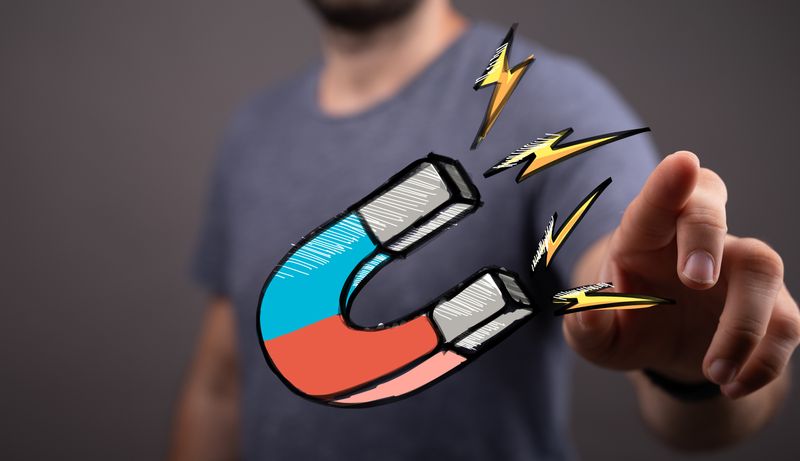 a guy pointing at the screen and a cartoon horseshoe magnet floats in front of him.