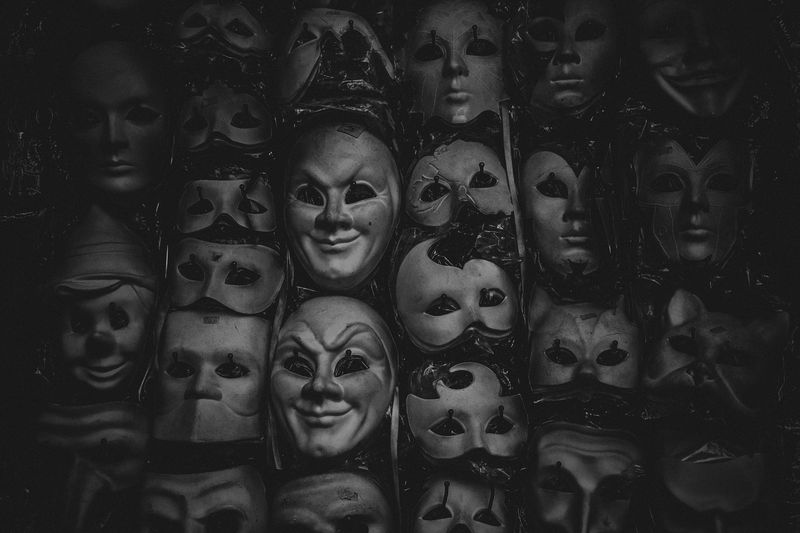 black and white shot of theatrical masks hanging on a wall