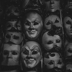 black and white shot of theatrical masks hanging on a wall