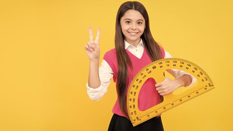 schoolgirl holding a giant protractor in one hand and making a 'peace' sign with the other