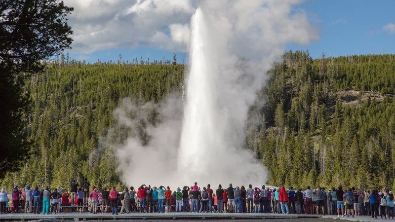 a crowd of tourists gathered around old faithful