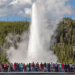 a crowd of tourists gathered around old faithful