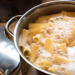 A large saucepan of penne-style pasta in boiling water 