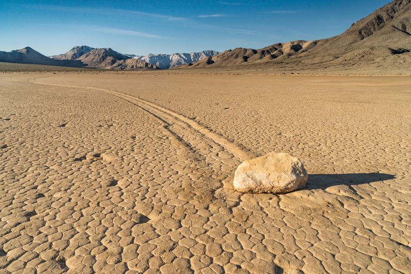 Vast playa, with a rock that has left a trail in the dried mud