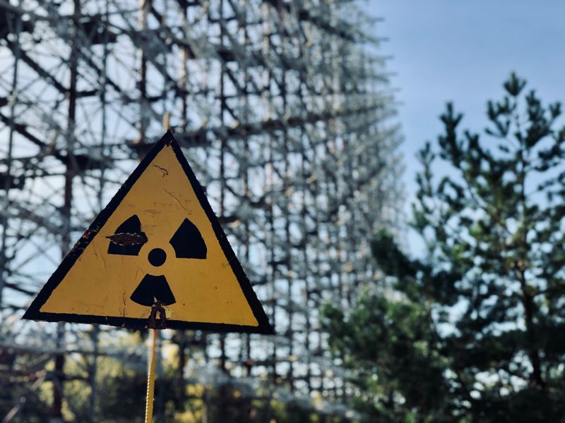 A radiation warning sign sits below the Duga array within the Chernobyl Exclusion Zone.
