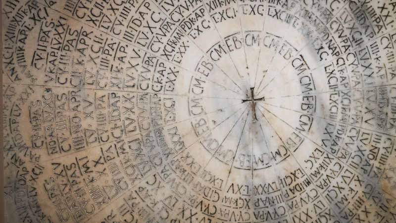 Ancient marble paschal calendar with circular Latin inscriptions and a central cross in the Cathedral of Ravenna