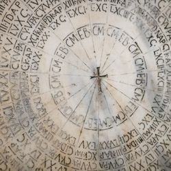 Ancient marble paschal calendar with circular Latin inscriptions and a central cross in the Cathedral of Ravenna