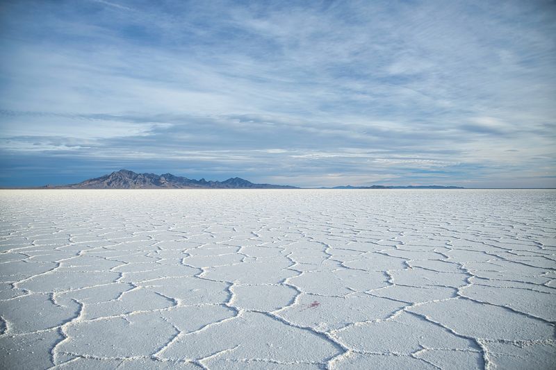 Salt flats stretch into the distance, white with ridges that give it texture despite being so flat 