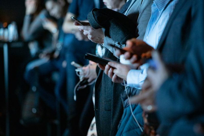 Row of people standing on their smartphone, technology 