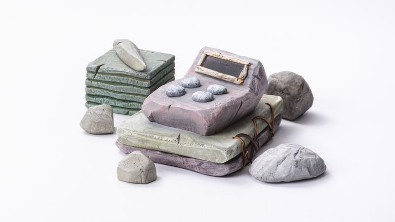 A computer rendering of a stone calculator and other desk items made from stone.