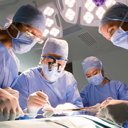 a groupof doctors and nurses stand around a patient in the sterile field of an operating theater