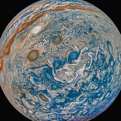 A beautiful prcoessed image of Jupiter showing it's swirling storms and gasses in reds, blues and greens using JUNO data.