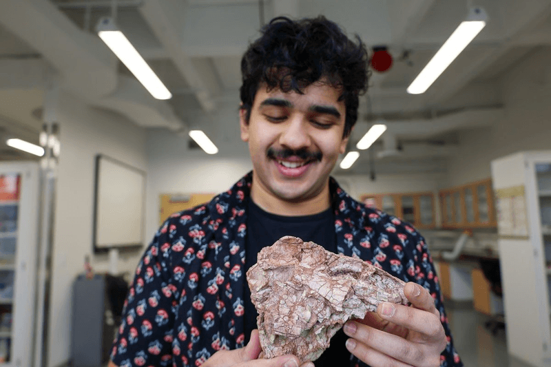 Simba Srivastava holding the "mangled murder muppet" skull that could change the thinking about late Triassic dinosaurs 