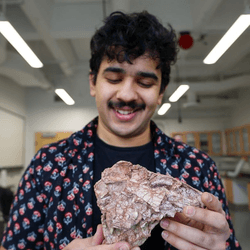 Simba Srivastava holding the "mangled murder muppet" skull that could change the thinking about late Triassic dinosaurs 
