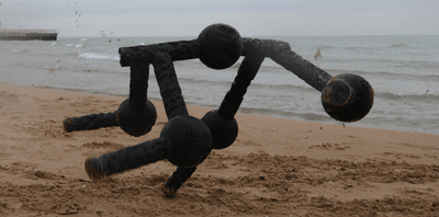 A quadruped robot with five modules takes a wander on the beach.