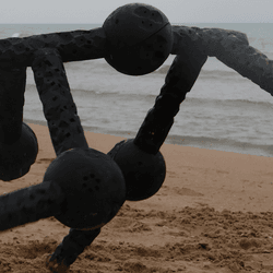 A quadruped robot with five modules takes a wander on the beach.