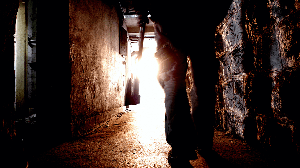 A man walking through a corridor with an axe.