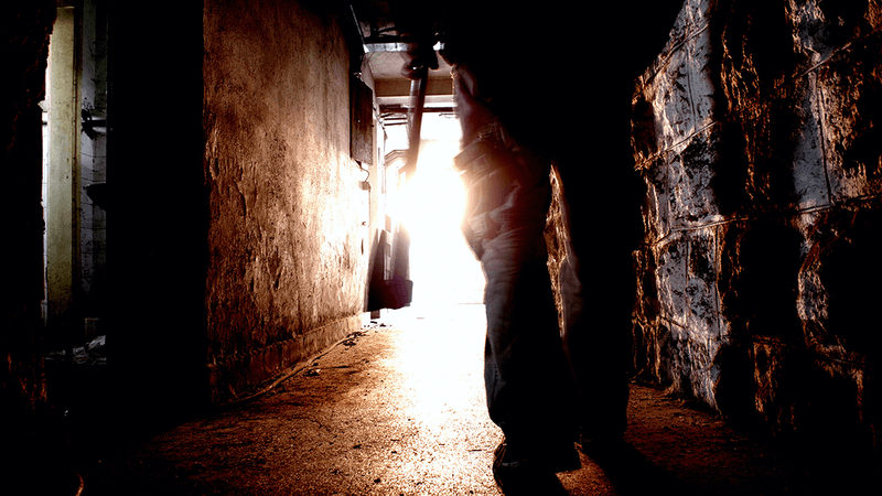 A man walking through a corridor with an axe.