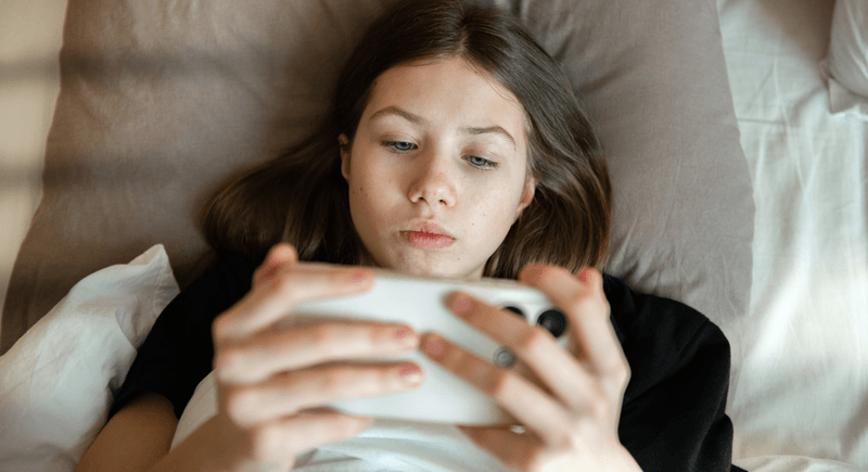 A girl, young teenager, on a smartphone looking at social media.