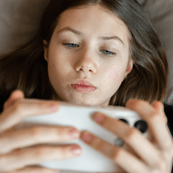 A girl, young teenager, on a smartphone looking at social media.